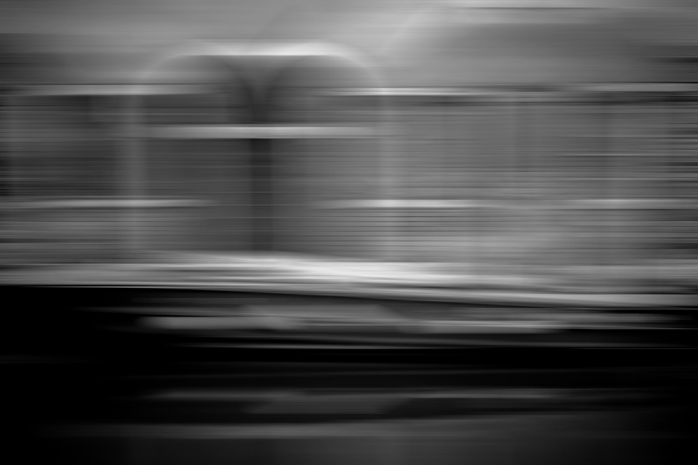 Black-and-white photograph: A horizontal blur of motion in bands of grey, white and black