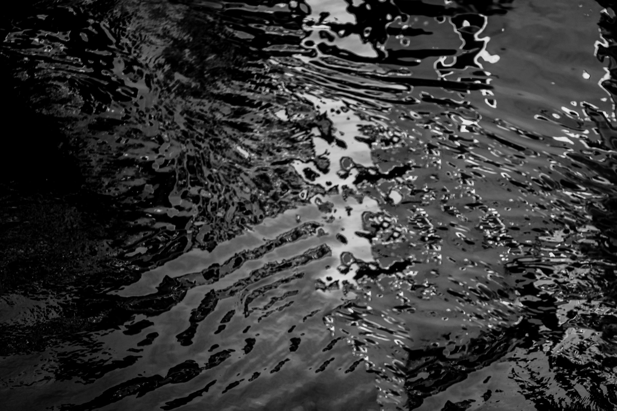 Black-and-white photograph: Light and shadow on rippling dark water